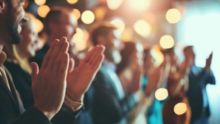 Colleagues giving a standing ovation to an awarded team member,