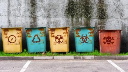 Vintage colored metal garbage containers with rusty signs of Not Approved, Radiation, Biohazard and Poison.