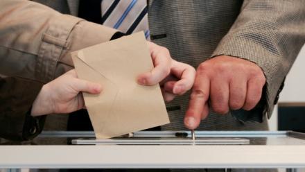 Image of hands placing ballot paper into ballot box