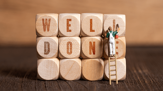 little painter figure and cubes showing the message &quot;well done&quot; on wooden background