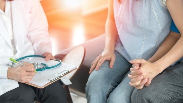 Married couple holding hands and talking to doctor