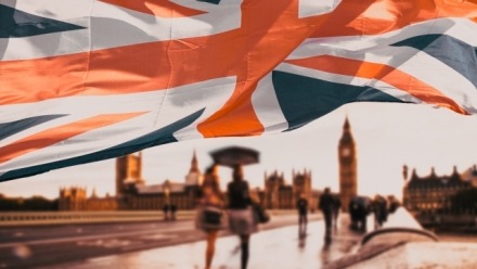 Image of flag of UK waving in front of Big Ben and Westmister Abbey London UK